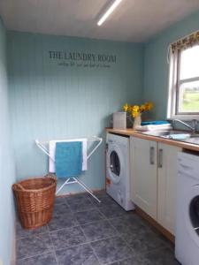 een wasruimte met een wasmachine en een wastafel bij Broadhaven Cottage, Freshwater East, Pembs in Pembroke