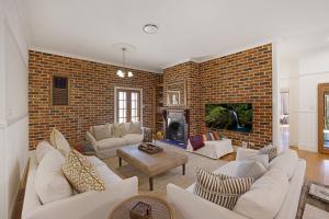 a living room with white furniture and a brick wall at Mia Mia Mudgee in Mudgee