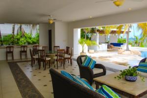 uma sala de estar com cadeiras e mesas e um pátio em Villa Santorini em Uaymitun