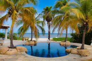 una piscina con palmeras y la playa en Villa Santorini, en Uaymitun