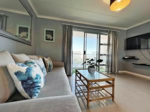 a living room with a couch and a table at Big Bay Beach Front Estate Apartment in Cape Town