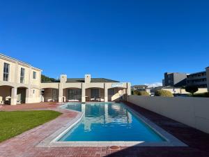 a swimming pool in front of a building at Big Bay Beach Front Estate in Cape Town