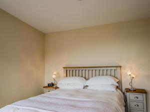 1 dormitorio con 1 cama con sábanas y almohadas blancas en The Cabin, en Lonmore