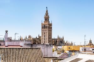 Un palazzo alto con una torre dell'orologio in una città di Apartament New Cathedral a Siviglia