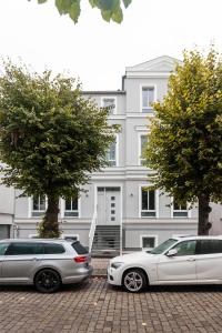 two cars parked in front of a white building at LIGHTHOUSE APPARTEMENTS in Warnemünde