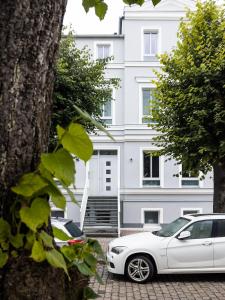 una macchina bianca parcheggiata di fronte a un edificio di LIGHTHOUSE APPARTEMENTS a Warnemünde