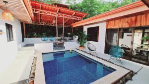 una piscina al aire libre con sillas y una casa en Villa Cocos la Fortuna, en Fortuna