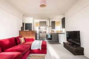 ein Wohnzimmer mit einem roten Sofa und einer Küche in der Unterkunft Worthing sea-front 3 bed apartment in Worthing + 14 Fotos