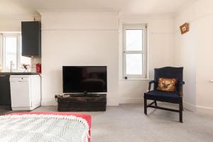 ein Wohnzimmer mit einem Stuhl und einem Flachbild-TV in der Unterkunft Worthing sea-front 3 bed apartment in Worthing