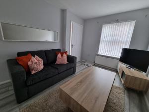 a living room with a couch and a coffee table at Beautiful 4 bed home, Sleeps 8, driveway parking, With sky & BT sports in Manchester