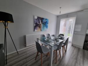 a dining room with a glass table and chairs at Beautiful 4 bed home, Sleeps 8, driveway parking, With sky & BT sports in Manchester