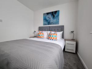1 dormitorio blanco con 1 cama grande con almohadas de color naranja en Beautiful 4 bed home, Sleeps 8, driveway parking, With sky & BT sports, en Mánchester