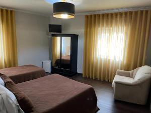 um quarto de hotel com duas camas e uma cadeira e um espelho em Residencial Solar da Estação em Barcelos