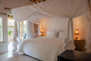 a bedroom with a white bed with white drapes at Maion Hotel e Boutique in Praia do Espelho