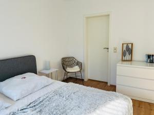 ein weißes Schlafzimmer mit einem Bett und einem Stuhl in der Unterkunft Connect 9.3 in Dorum Neufeld