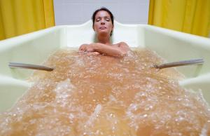 a woman in a bath tub with a baby in it at Medical SPA "Eglės sanatorija" Standard Druskininkai in Druskininkai