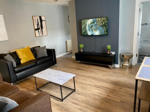 Una sala de estar con un sofá negro y una mesa. en Pendle House - Apartment 3, en Colwyn Bay