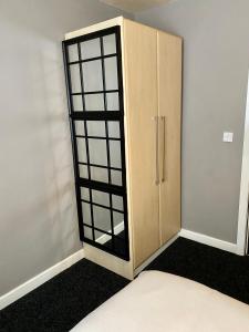 um armário de madeira com portas de vidro num quarto em Pendle House - Apartment 3 em Colwyn Bay