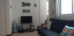 sala de estar con sofá azul y TV de pantalla plana en Pura Vida Condo, en Tamarindo
