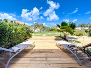 a deck with two lounge chairs and a palm tree at Costa Blue, Orient Bay beach front, XXL pools in Orient Bay