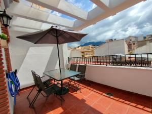 einen Tisch und Stühle auf einem Balkon mit Sonnenschirm in der Unterkunft Ático Granada al Sol (terraza vistas montaña) in La Zubia
