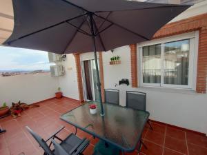 einen Tisch und Stühle mit Sonnenschirm auf einer Terrasse in der Unterkunft Ático Granada al Sol (terraza vistas montaña) in La Zubia