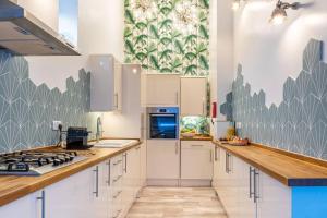 a kitchen with white cabinets and blue and green wallpaper at Style & opulence in Georgian chapel w Parking in Bath