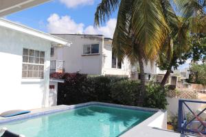 a swimming pool in front of a house at Little Reef Villa in Saint James