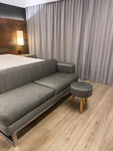 a room with a bed and a couch and a stool at Flat particular incrível dentro do hotel M Ibirapuera em Moema in São Paulo
