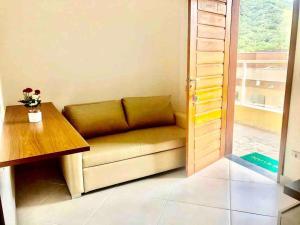 a couch in a room with a table and a window at Rafael Apartamentos 800m da Praia da Maranduba in Ubatuba