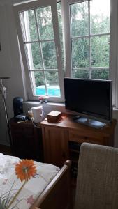 1 dormitorio con TV, escritorio y cama en B&B de (S)tulp, en Retie