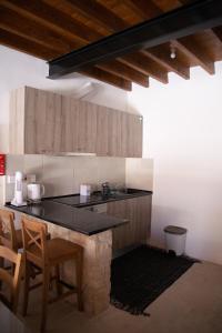 une cuisine avec un comptoir noir et des placards en bois dans l'établissement Cleo's Inn, à Lófou