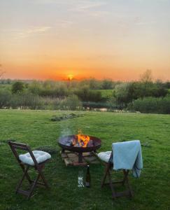 a fire pit in a field with two chairs and a table at Pasterhof Eichhorst in Friedland