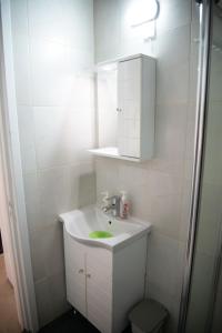 Baño blanco con lavabo y espejo en Cleo's Inn, en Lofou