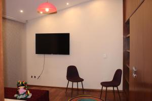 sala de estar con 2 sillas y TV en la pared en Casa Luna Coyoacan, en Ciudad de México