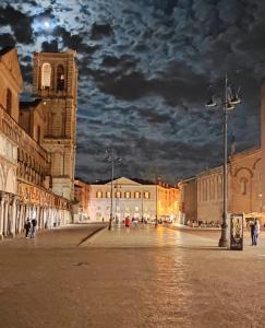 una strada di città di notte con una torre dell'orologio di Be Happy a Ferrara