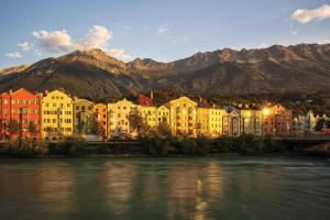 eine Gruppe von Gebäuden neben einem Fluss mit Bergen in der Unterkunft Urban Inn - Wilten 24/7 in Innsbruck