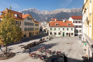 una calle de la ciudad con mesas, sillas y montañas en Urban Inn - Wilten 24/7, en Innsbruck