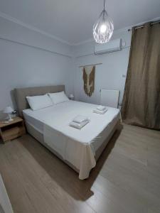 ein Schlafzimmer mit einem großen weißen Bett und einem Kronleuchter in der Unterkunft Blue Flag Glyfada Center in Athen
