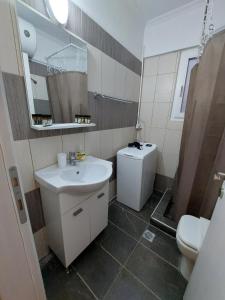 ein Badezimmer mit einem Waschbecken, einem WC und einem Spiegel in der Unterkunft Blue Flag Glyfada Center in Athen