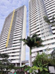 two tall buildings with palm trees in front of them at Apartamento completo/ Verano Ponta Negra- Natal in Natal