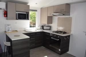 a kitchen with brown cabinets and a stove top oven at Mobilhome 526 3ch/2SDB camping 4* La Réserve SIBLU Gastes in Gastes
