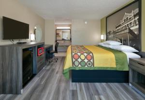 um quarto de hotel com uma cama e uma televisão de ecrã plano em Super 8 by Wyndham Mobile/Tillmans Corner em Tillmans Corner