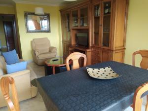 ein Wohnzimmer mit einem Tisch, Stühlen und einem TV in der Unterkunft Piso in Boiro