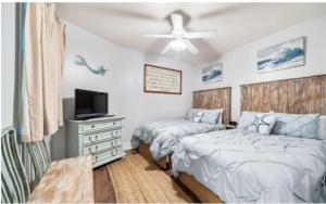 1 dormitorio con 2 camas, TV y tocador en Caribe Resort Unit C211, en Orange Beach