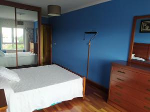 Schlafzimmer mit blauen Wänden, einem Bett und einer Kommode in der Unterkunft Piso in Boiro
