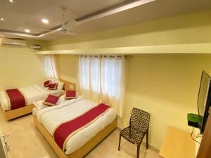 a bedroom with two beds and a chair and a television at Prabhuvihar Residency in Porvorim