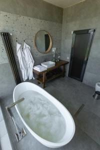 a bathroom with a tub and a sink and a mirror at CHALET PANORAMA NIKORTSMINDA in Nikortsminda