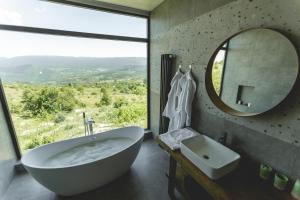 a bathroom with a tub and a mirror and a sink at CHALET PANORAMA NIKORTSMINDA in Nikortsminda
