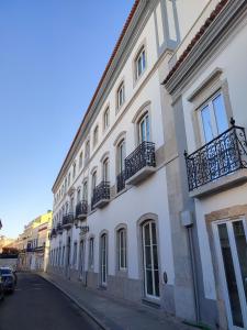 a large white building with balconies on a street at Offline Mood Apartment in Faro